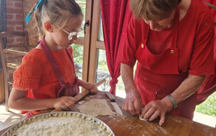 Donna che insegna ad una bambina a fare una torta della Lunigiana
