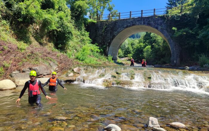Un gruppo discende il torrente con muta, caschetto e giubbotto salvagente durante l'escursione Francigena River Trekking